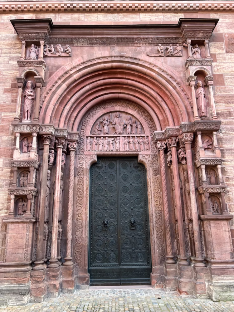 Most of the present Basler Münster is Gothic but arguably the most impressive single feature of the Basel Minster is the highly decorative Romanesque St Gallen portal (Galluspforte). On the tympanum, dating from around 1180, is a relief of Christ sitting in judgment. The Galluspforte also has reliefs of the wise and foolish virgins from the parable described in the New Testament