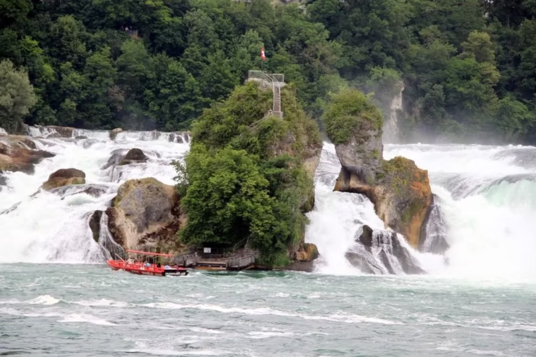 Boat landing passengers at a rock in the Rheinfall