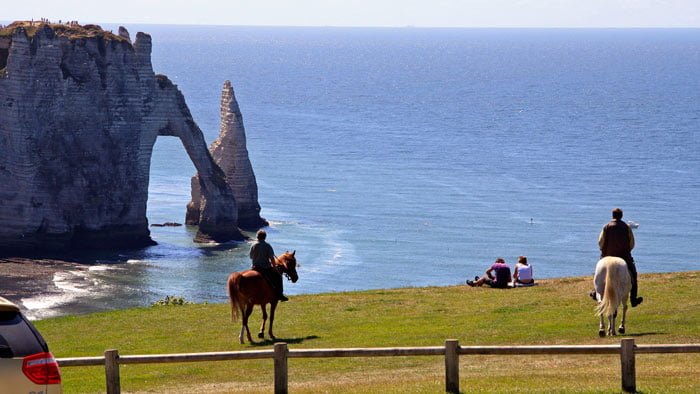 Horse riders and view of arch at Etretat that may be reached from Paris on public transportation in less than three hours.