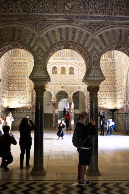 The top tips for seeing the Real Alcazar de Sevilla are to buy skip-the-line tickets online in advance and to enter the palace complex in the late afternoon to avoid tour groups. Photographers in the Hall of the Ambassadors