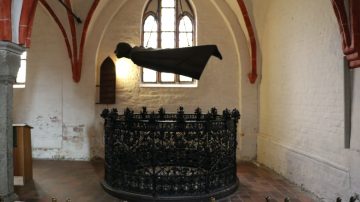 Barlach's Der Schwebende hovers over a Renaissance wrought metal trellis in the Güstrower Dom